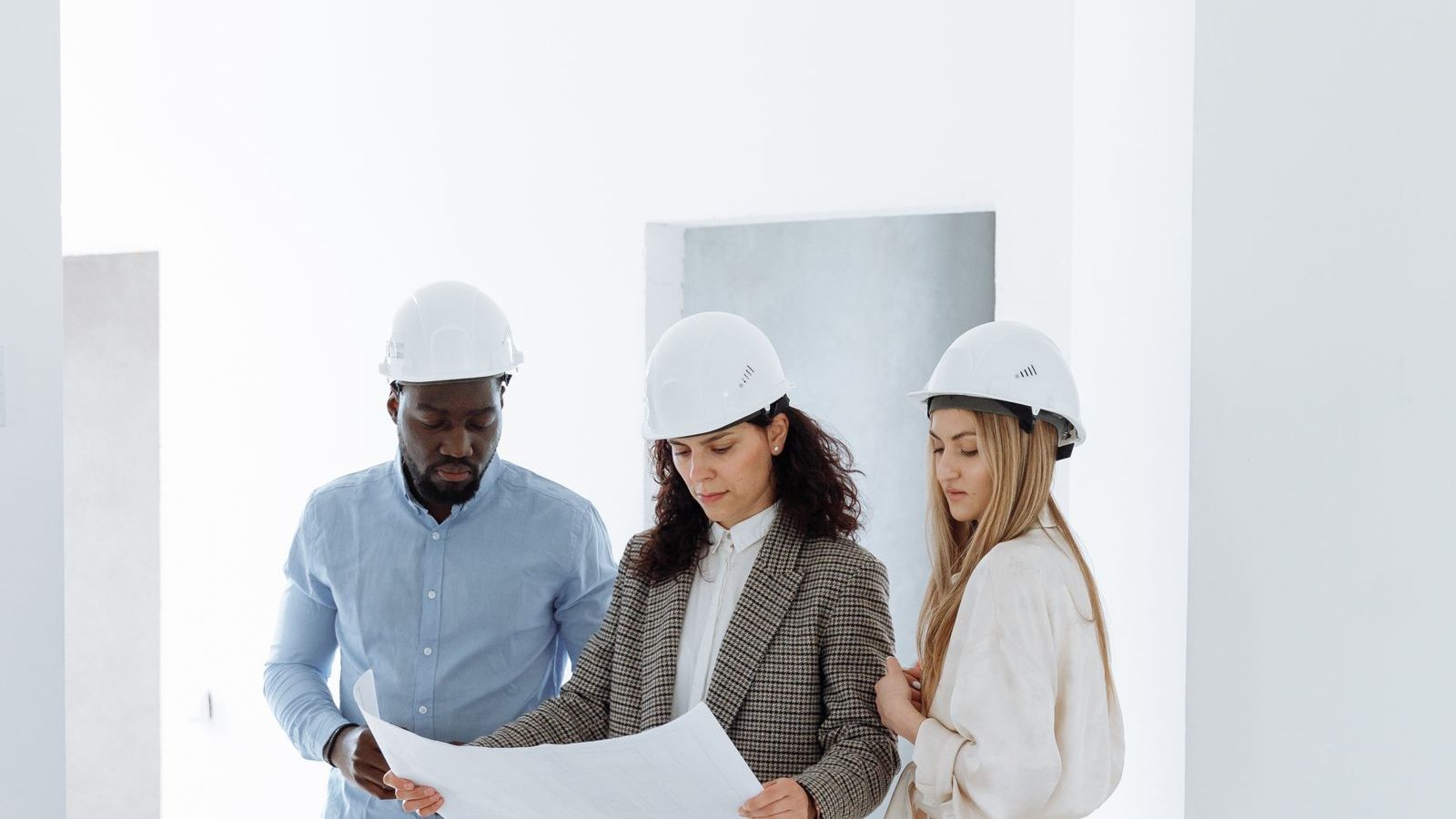 Contractor team in hard hats reviewing building plans inside a newly built home